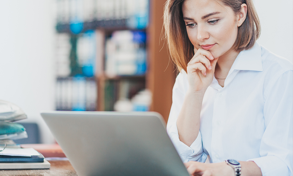 Woman smiling while looking over loan information on a laptop.